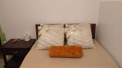 a bed with white pillows and a brown box on it at Mabs Hostel in El Nido
