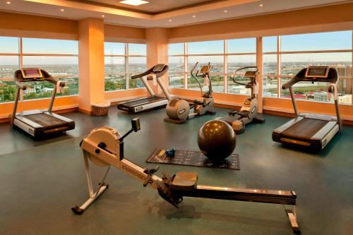 einen Fitnessraum mit Laufbändern und Crosstrainern in einem Gebäude mit Fenstern in der Unterkunft Atyrau Executive Apartments in Atyrau