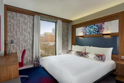 a bedroom with a large white bed and a window at Aloft Birmingham Eastside in Birmingham
