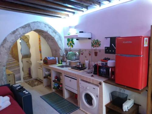a kitchen with a red refrigerator and a washing machine at The little house of Ely in Siracusa