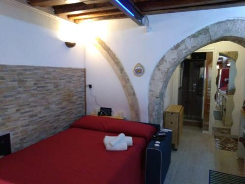 a bedroom with a red bed and a brick wall at The little house of Ely in Siracusa