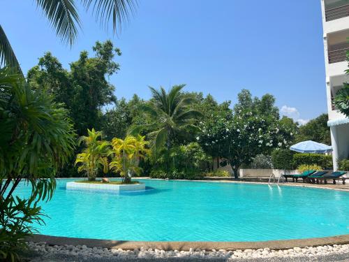 羅勇的住宿－sea sand sun resort Executive Mae Rumphueng beach，一座种植了棕榈树的大型蓝色游泳池和一座建筑