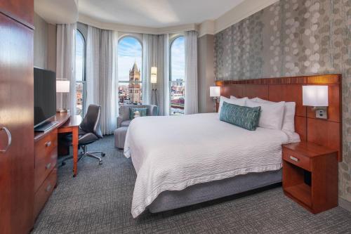 um quarto de hotel com uma cama, uma secretária e uma televisão em Courtyard Boston Copley Square em Boston