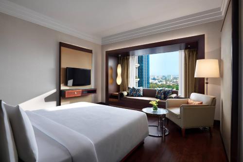バンガロールにあるJW マリオット ホテル ベンガルールのベッド、ソファ、テレビが備わるホテルルームです。