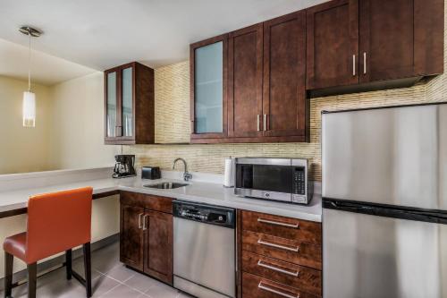a kitchen with wooden cabinets and a refrigerator at Residence Inn by Marriott Charlotte City Center in Charlotte