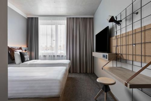 a hotel room with two beds and a tv at Moxy Bremen in Bremen