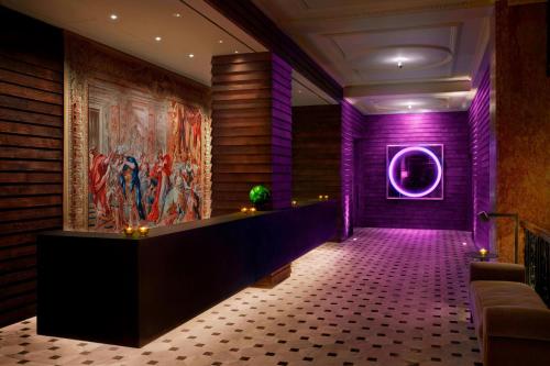 a lobby with purple lighting and a painting on the wall at The London EDITION in London