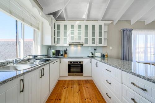 a kitchen with white cabinets and a wooden floor at The Slipway in Colchester