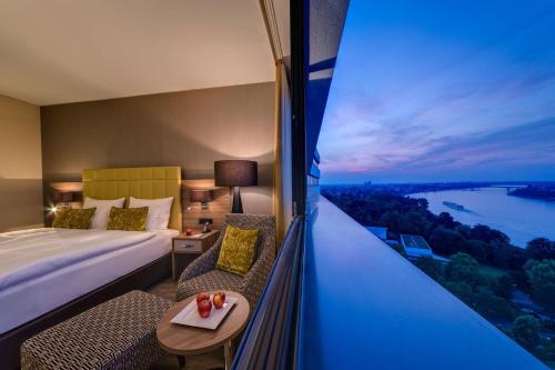 ボンにあるボン マリオット ホテルのベッド1台、景色を望む窓が備わるホテルルームです。
