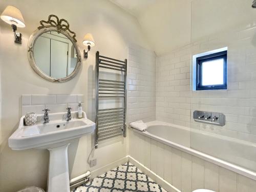 W łazience znajduje się umywalka, wanna i lustro. w obiekcie Primrose Lodge w mieście Mayfield