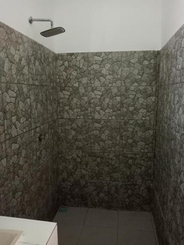 a bathroom with a stone wall with a shower at Ani Bungalows in Gili Trawangan