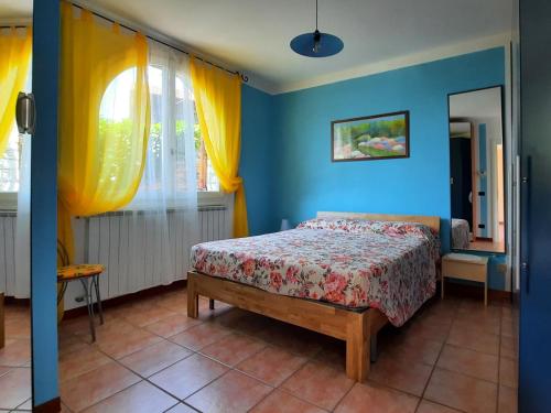Schlafzimmer mit einem Bett mit blauen Wänden und gelben Vorhängen in der Unterkunft Appartamento Porto 1 in Cannero Riviera