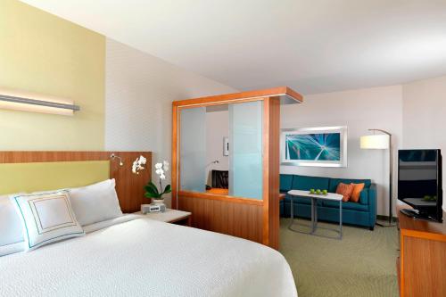 SpringHill Suites by Marriott Lake Charles في ليك تشارلز: غرفة نوم مع سرير وغرفة معيشة