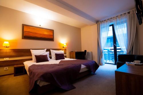um quarto de hotel com uma cama grande e uma janela em GreenHill Brasov em Brasov