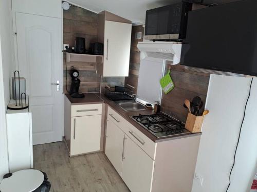 a small kitchen with a stove and white cabinets at A la ferme dans le Luberon 