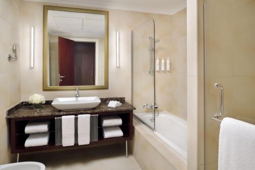 a bathroom with a sink and a shower and a tub at Marriott Executive Apartments Manama, Bahrain in Manama