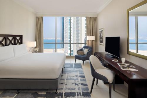 ein Hotelzimmer mit einem Bett, einem Schreibtisch und einem Schlafzimmer in der Unterkunft Marriott Executive Apartments Manama, Bahrain in Manama