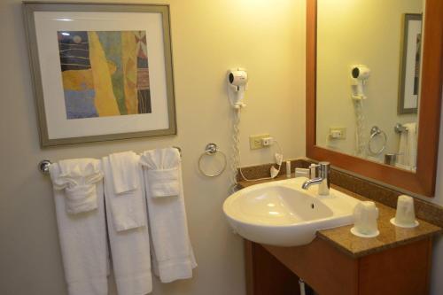 ein Badezimmer mit einem Waschbecken, einem Spiegel und Handtüchern in der Unterkunft Courtyard Aguadilla in Aguadilla