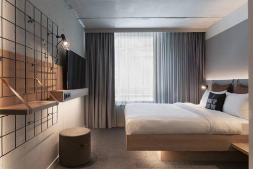 a hotel room with a bed and a window at Moxy Frankfurt City Center in Frankfurt/Main