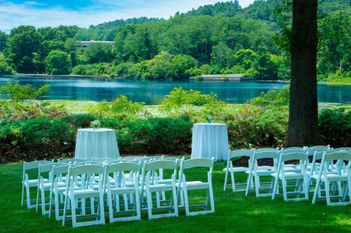 a group of white chairs sitting in the grass near a lake at Boston Marriott Newton in Newton