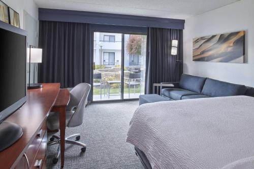 a hotel room with a bed and a desk and a television at Courtyard by Marriott Detroit Troy in Troy
