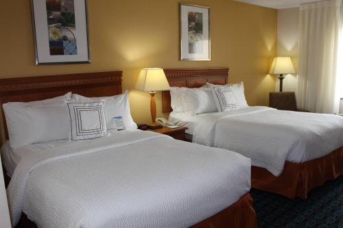 a hotel room with two beds with white sheets at Fairfield Inn & Suites Kansas City Liberty in Liberty