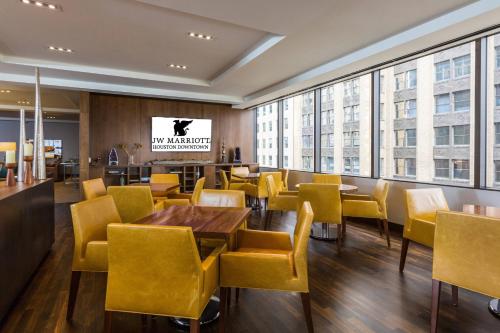 a restaurant with yellow chairs and tables and windows at JW Marriott Houston Downtown in Houston