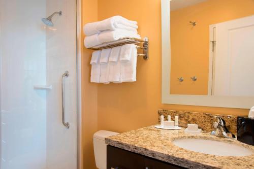 a bathroom with a sink and a shower with towels at TownePlace Suites by Marriott Champaign in Champaign