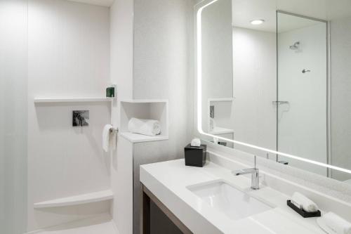 Baño blanco con lavabo y espejo en Courtyard by Marriott Houston Heights/I-10 en Houston