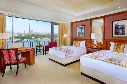 a hotel room with two beds and a desk at The Nile Ritz-Carlton, Cairo in Cairo