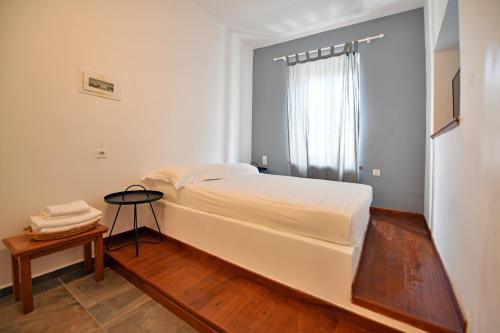 een slaapkamer met een groot wit bed en een tafel bij Piteoussa in Hydra