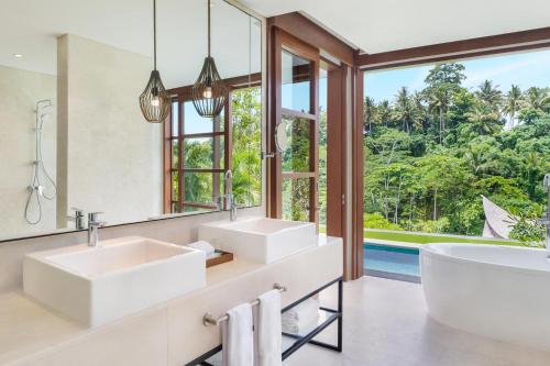 La salle de bains est pourvue de 2 lavabos, d'une baignoire et d'un grand miroir. dans l'établissement The Westin Resort & Spa Ubud, Bali, à Ubud