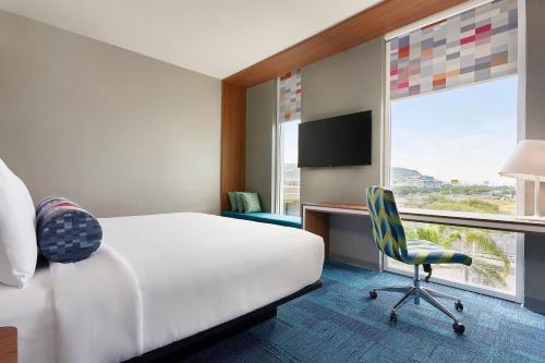 a hotel room with a bed and a chair and a window at Aloft Queretaro in Querétaro
