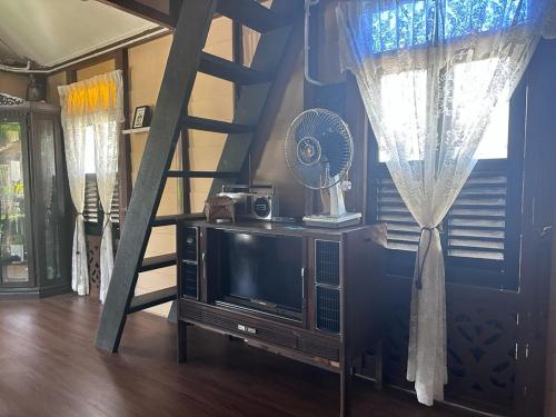 a room with a tv and a fan and a ladder at Pondok Tok Wan Homestay in Kampong Kubang Bemban