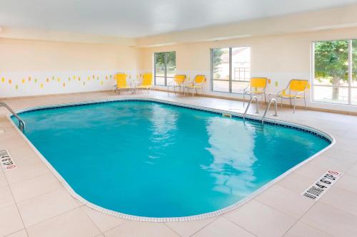 Una gran piscina en una habitación con sillas y mesas. en Fairfield Inn & Suites Kansas City Lee's Summit, en Lee's Summit