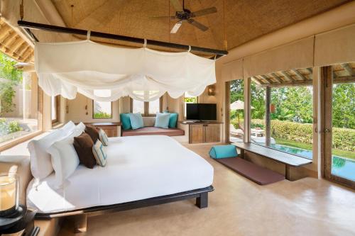 a bedroom with a large bed and a pool at The Naka Island, a Luxury Collection Resort & Spa, Phuket in Ko Naka