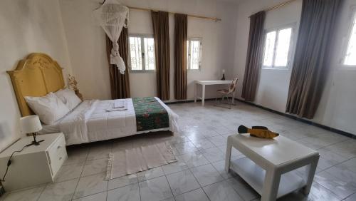 a bedroom with a bed and a table and windows at Le k in Nouakchott