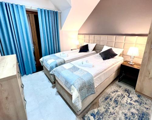a bedroom with two beds and blue curtains at ELFF -Apartamenty i pokoje gościnne in Cisna