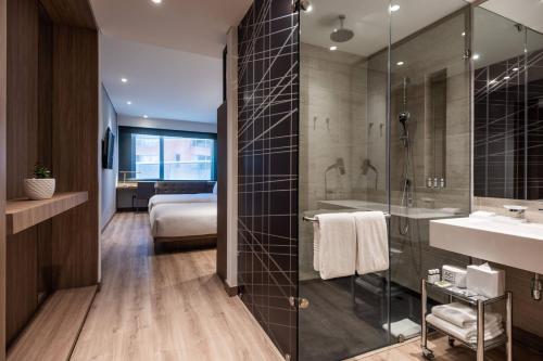 a bathroom with a shower and a sink and a bed at AC Hotel by Marriott Bogota Zona T in Bogotá