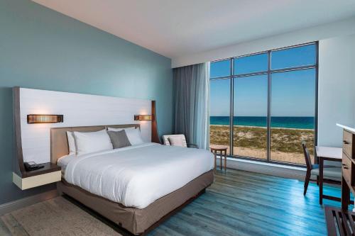 SpringHill Suites by Marriott Navarre Beach في نافار: غرفة نوم مع سرير وإطلالة على المحيط