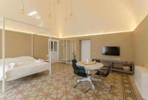 a bedroom with a bed and a table and a tv at Palazzo Junno Dimora D'Epoca in Mattinata