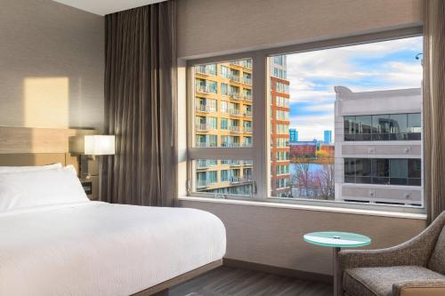 a bedroom with a bed and a large window at AC Hotel by Marriott Boston North in Medford