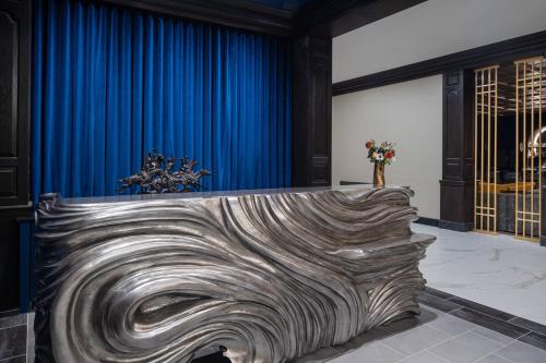 a room with a large wooden sculpture in front of a blue curtain at The Drake Oak Brook, Autograph Collection in Oak Brook