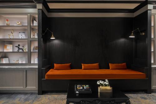 an orange bed in a black room with a black wall at The Drake Oak Brook, Autograph Collection in Oak Brook