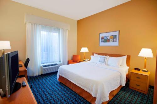 a hotel room with a bed and a flat screen tv at Fairfield Inn & Suites by Marriott Detroit Metro Airport Romulus in Romulus