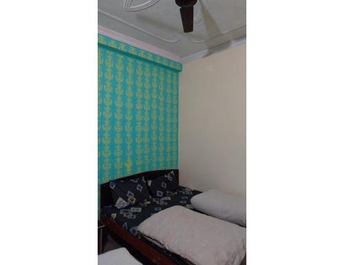 a room with a bed and a green wall at Hotel Gaurishankar Palace, Barkot in Barkot