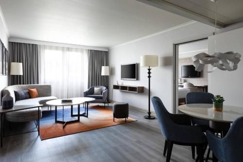 een woonkamer met een tafel en stoelen en een woonkamer bij Paris Marriott Charles de Gaulle Airport Hotel in Roissy-en-France