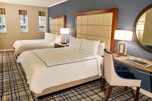 a bedroom with two beds and a desk and a mirror at The Adolphus, Autograph Collection in Dallas