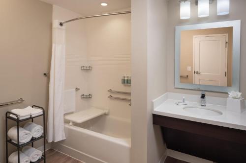 a bathroom with a sink and a tub and a mirror at TownePlace Suites Miami Kendall West in Kendall