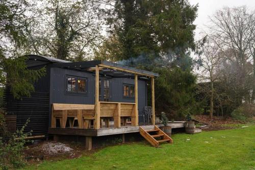 a black tiny house sitting in a yard at Shepherds Hut in countryside near Bath and Bristol in Bristol